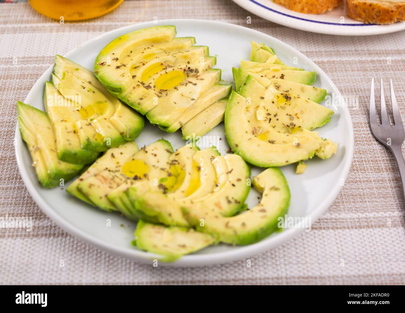 Reifes Avocado-Fruchtfleisch in Stücke geschnitten, mit Zitronensaft auf einem Teller bestreut Stockfoto