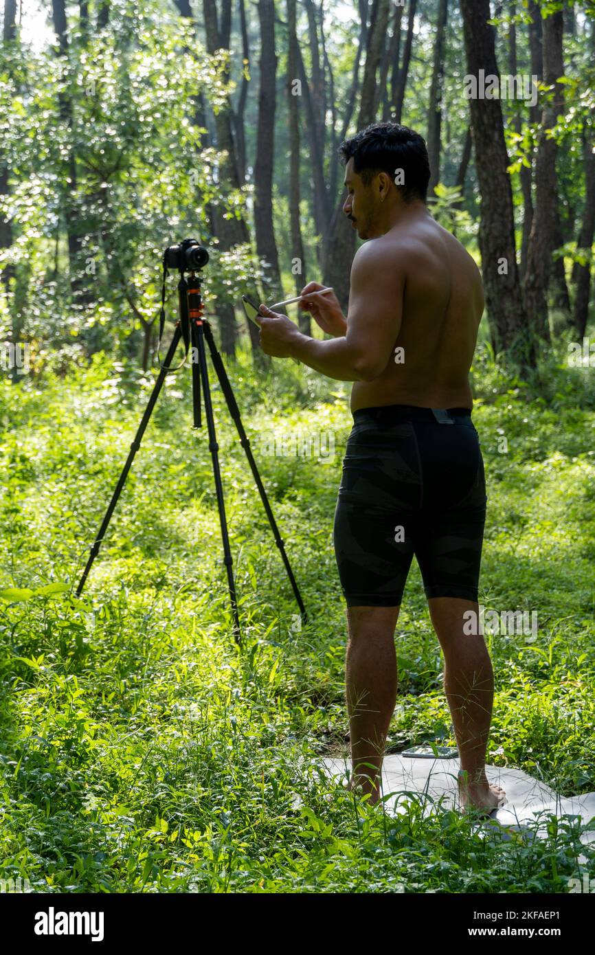 Ein Mann führt einen virtuellen Fitnesskurs mit einer Gruppe von Menschen zu Hause auf einer Videokonferenz durch Stockfoto
