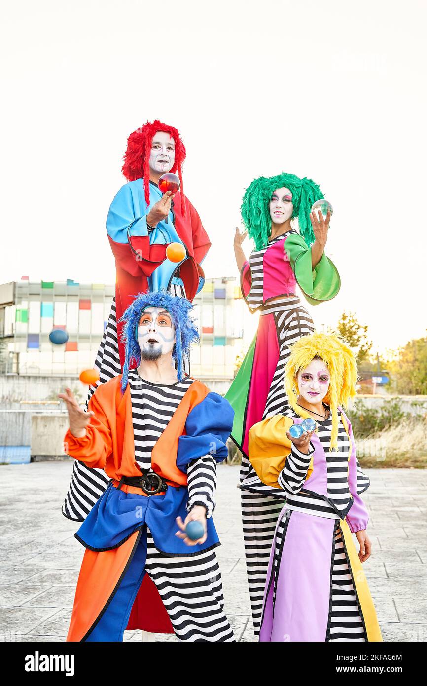 Männliche und weibliche Clowns in farbenfrohen Kostümen und Perücken, die auf die Kamera blicken, die Kristallkugeln in den Händen hält. Stockfoto