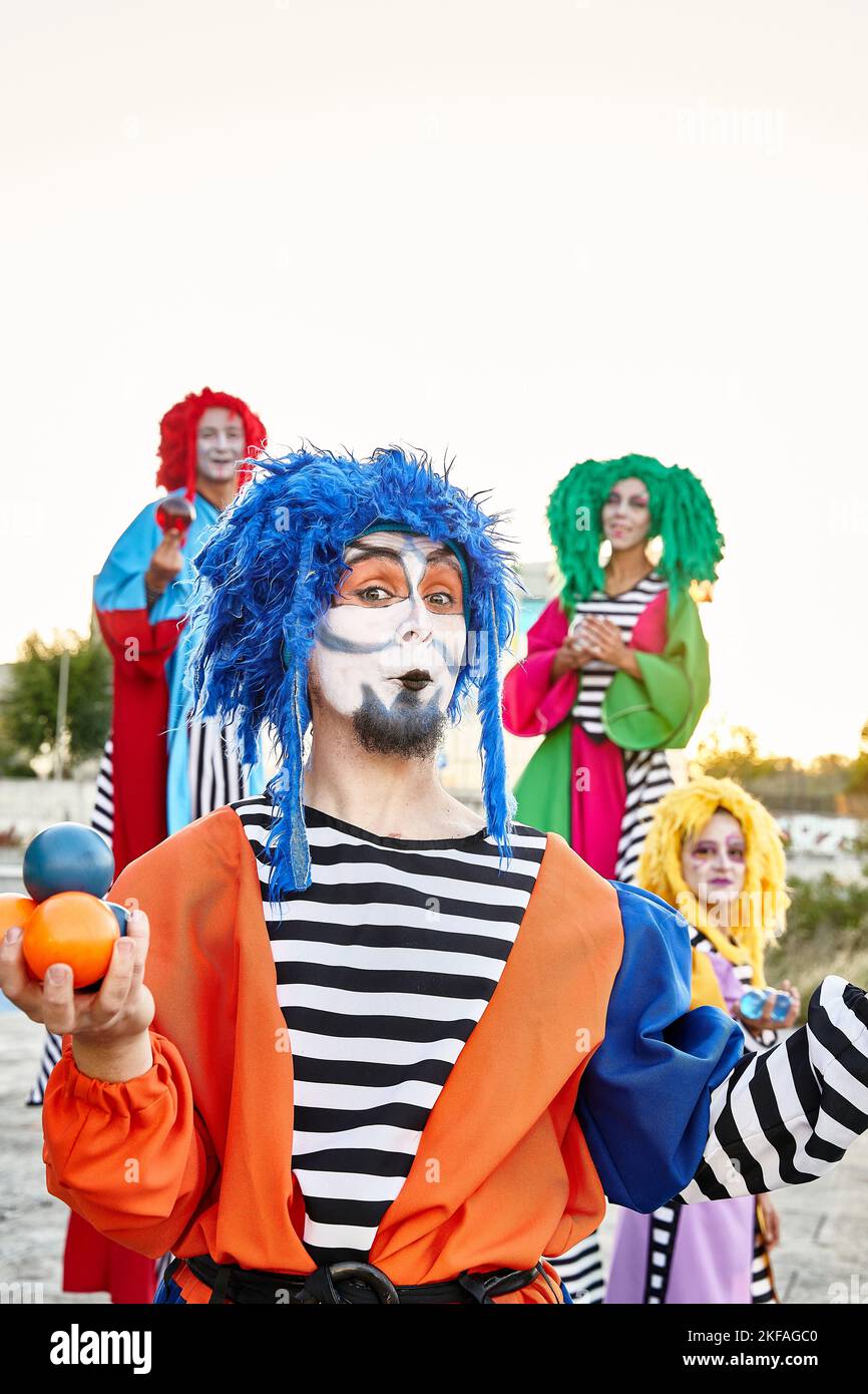 Männliche und weibliche Clowns in farbenfrohen Kostümen und Perücken, die auf die Kamera blicken, die Kristallkugeln in den Händen hält. Stockfoto