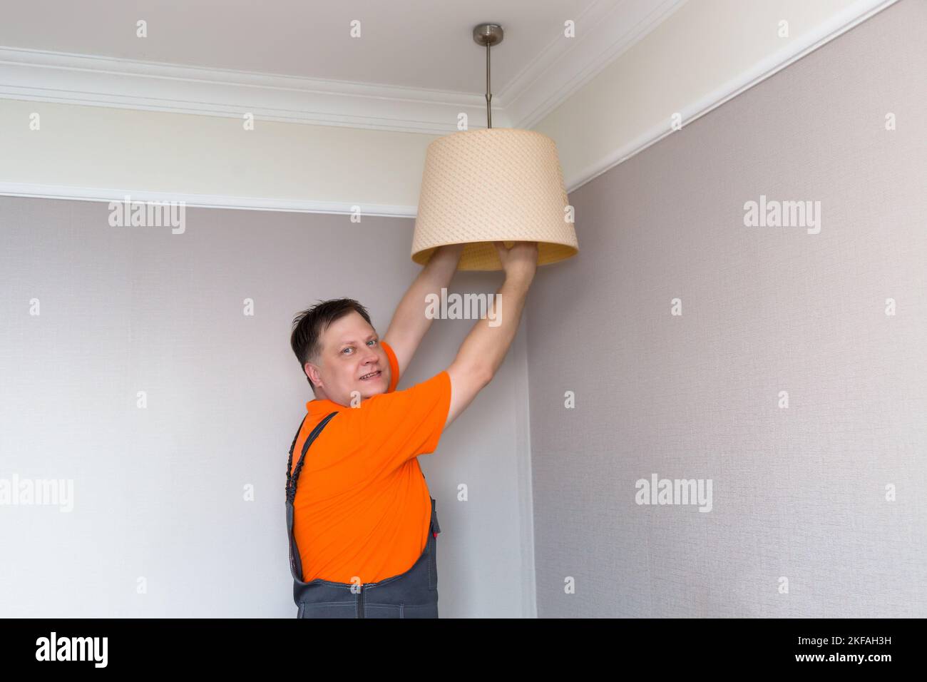 Ein Elektriker wechselt die elektrische Lampe in einer Lampe. Stockfoto