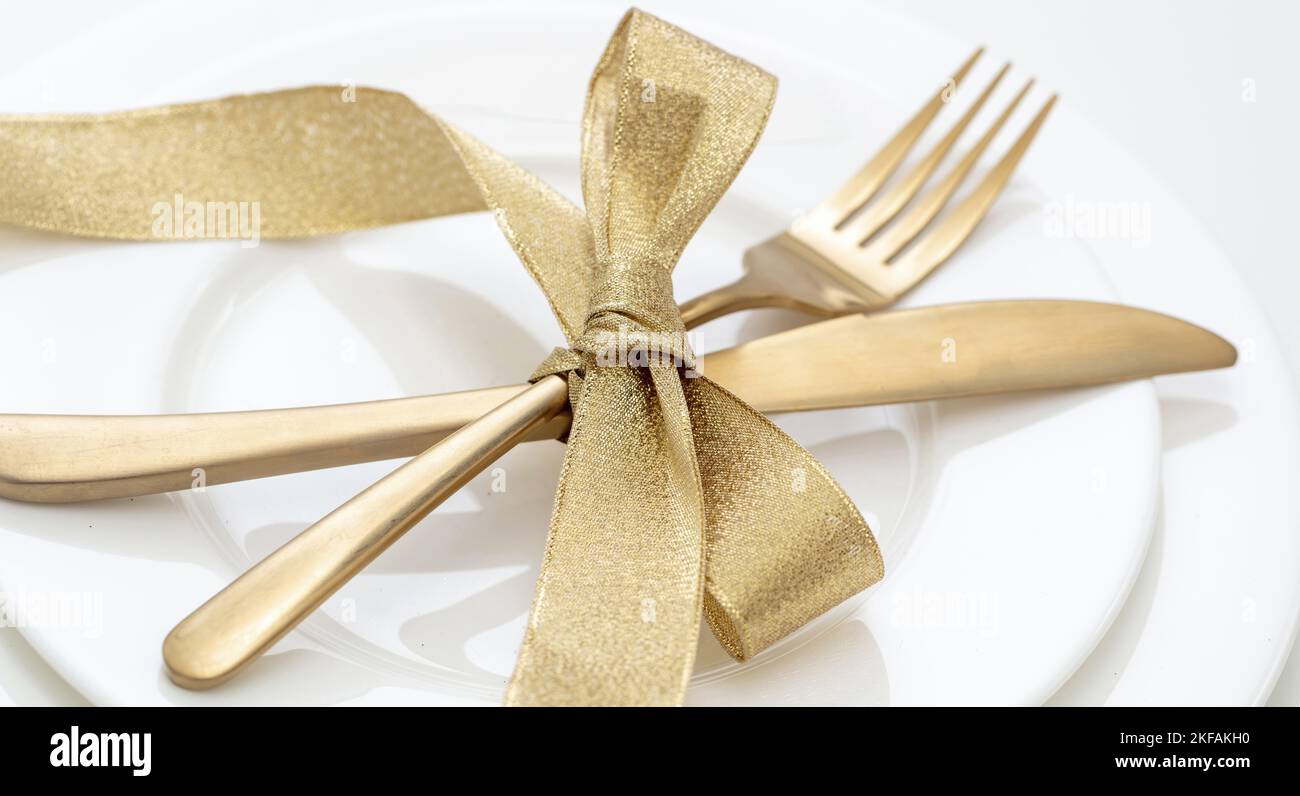 Weihnachtliche Tischaufstellung Nahaufnahme. Goldenes Besteck und Dekoration auf weißen Gerichten, elegantes Restaurant, Festessen Stockfoto