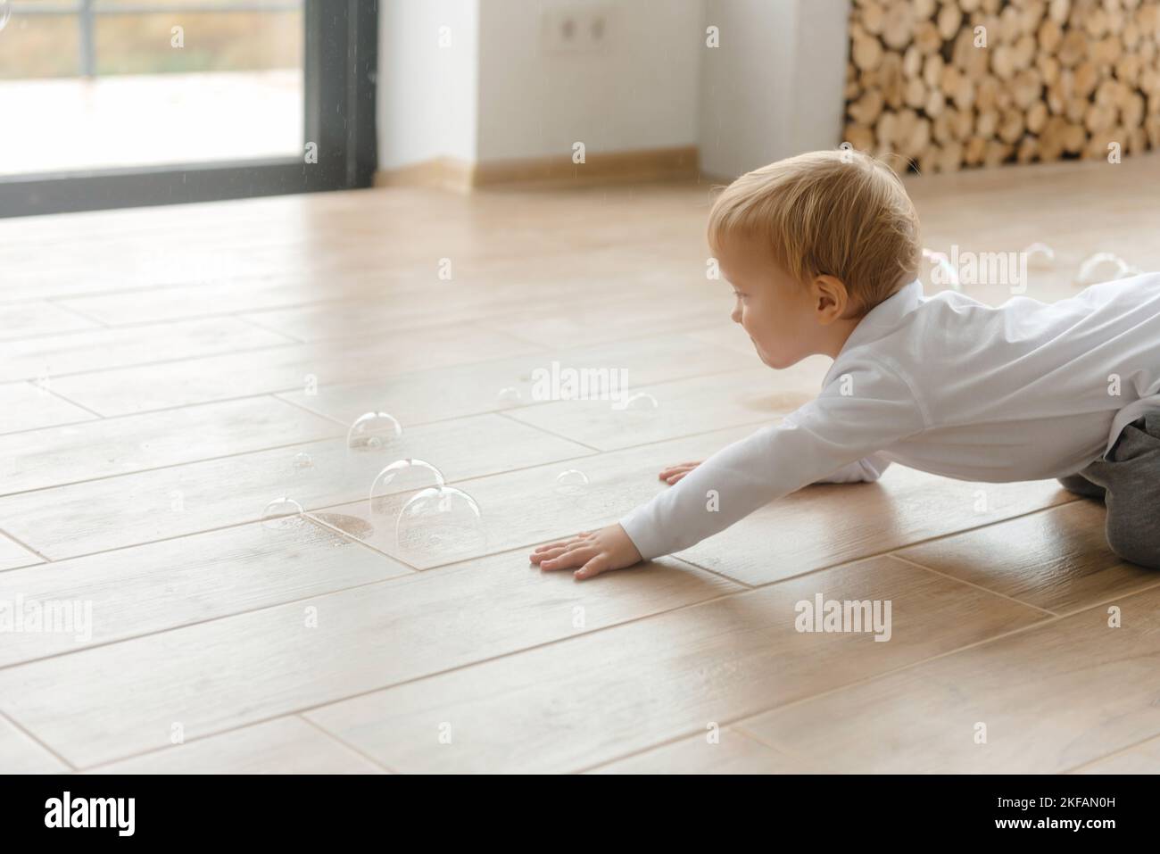 Das Kind kriecht auf den Boden und platzt Seifenblasen Stockfoto