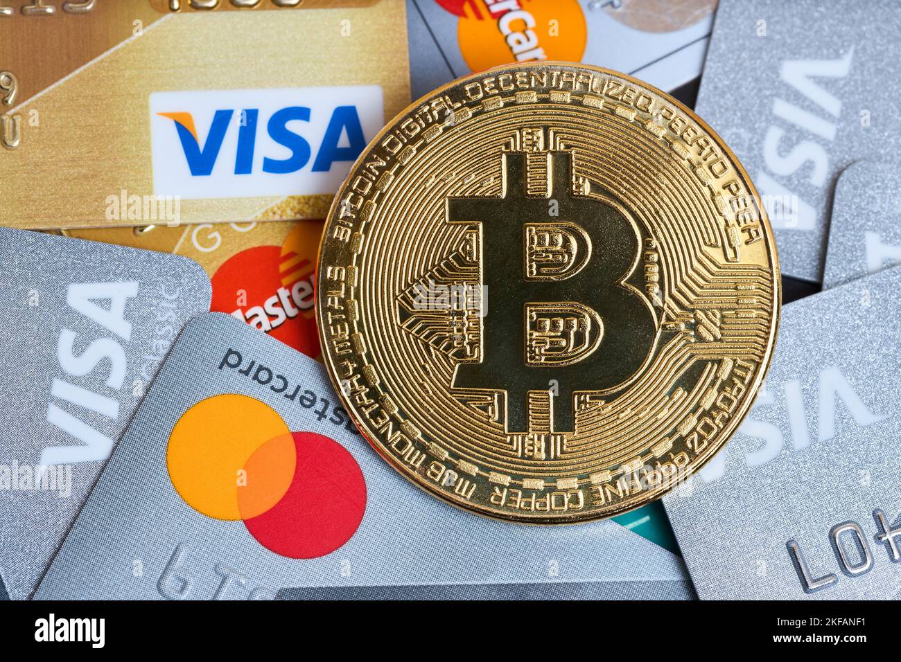 Berlin - November 2022: Bitcoin Goldmünze und Debitkarten Visa und MasterCard. Visa Gold und MasterCard Plastikkarten Haufen Makro Nahaufnahme Hintergrund Stockfoto