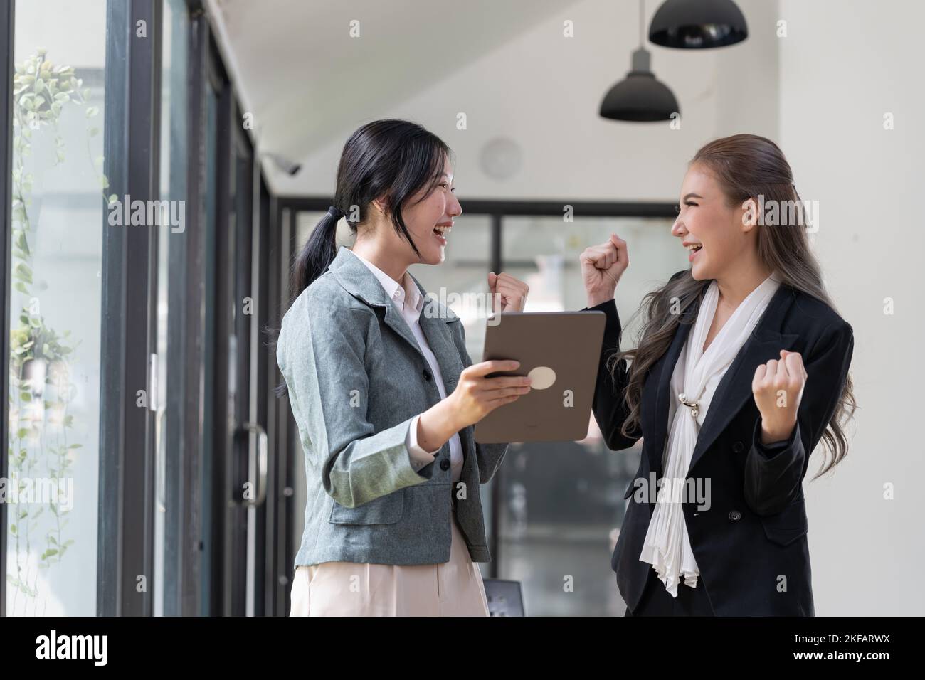 Das junge asiatische Business-Team feiert einen Triumph mit den Waffen. Stockfoto