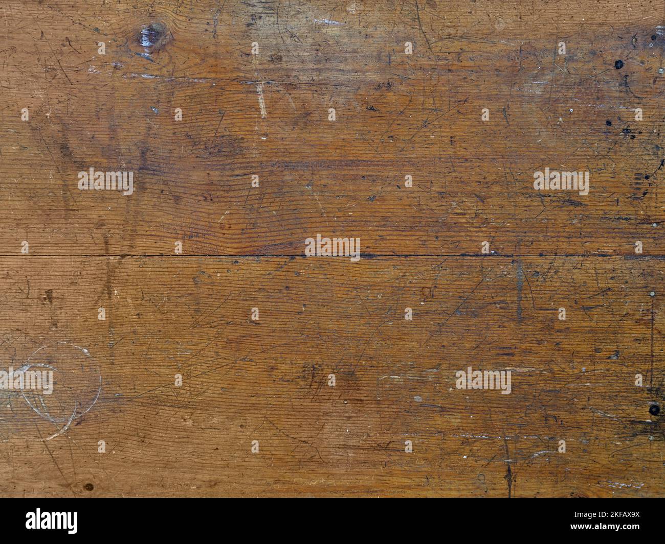 Kratzer und allgemeine Abnutzung werden auf der Oberfläche eines alten Holztisches detailliert dargestellt. Stockfoto