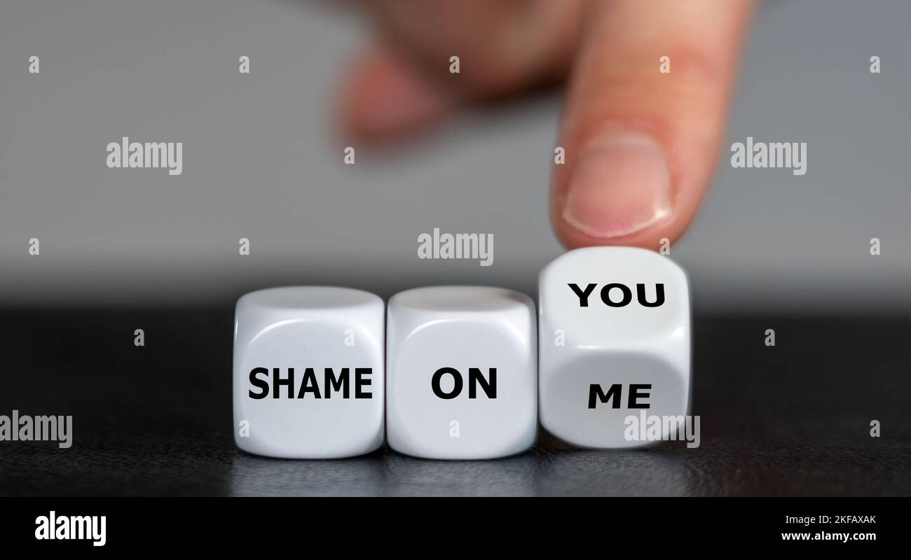 Die Hand dreht Würfel und ändert den Ausdruck 'Shame auf mich' in 'Shame auf dich'. Stockfoto