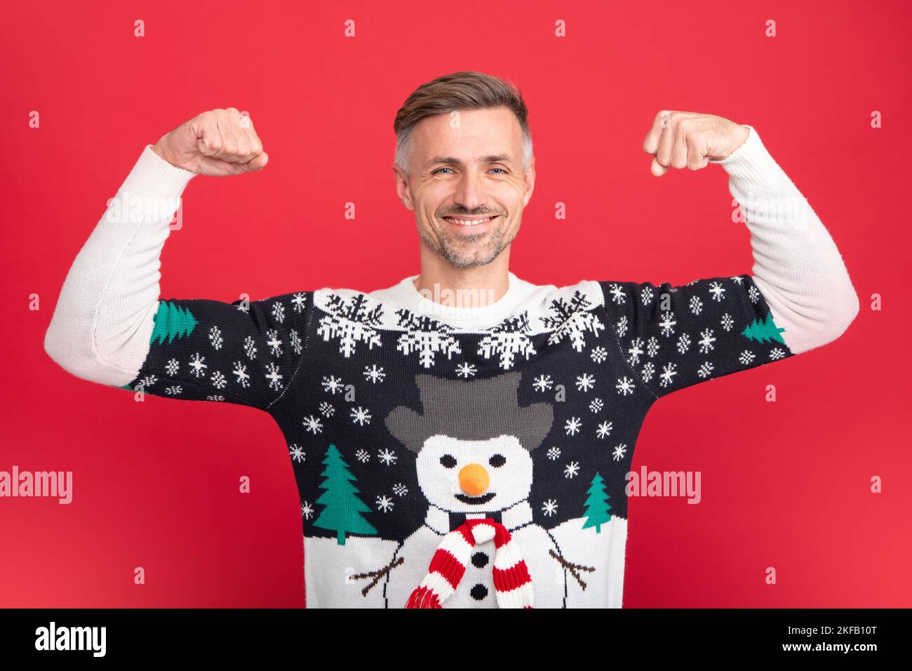 Studio Portrait von Kerl trägt weihnachtsmann Hut und Winter Pullover. Mann mit weihnachtshut auf isoliertem rotem Hintergrund. Stockfoto