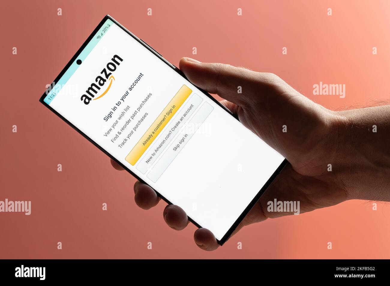 New york, USA - 10. November 2022: Melden Sie sich für Amazon Shopping auf dem Smartphone mit der Hand Nahaufnahme auf rosa Hintergrund Stockfoto