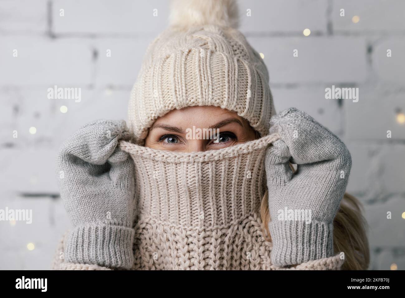 Frau versteckt Gesicht in Wolle Winter Pullover. Kaltes Wetter Kleidung Stockfoto