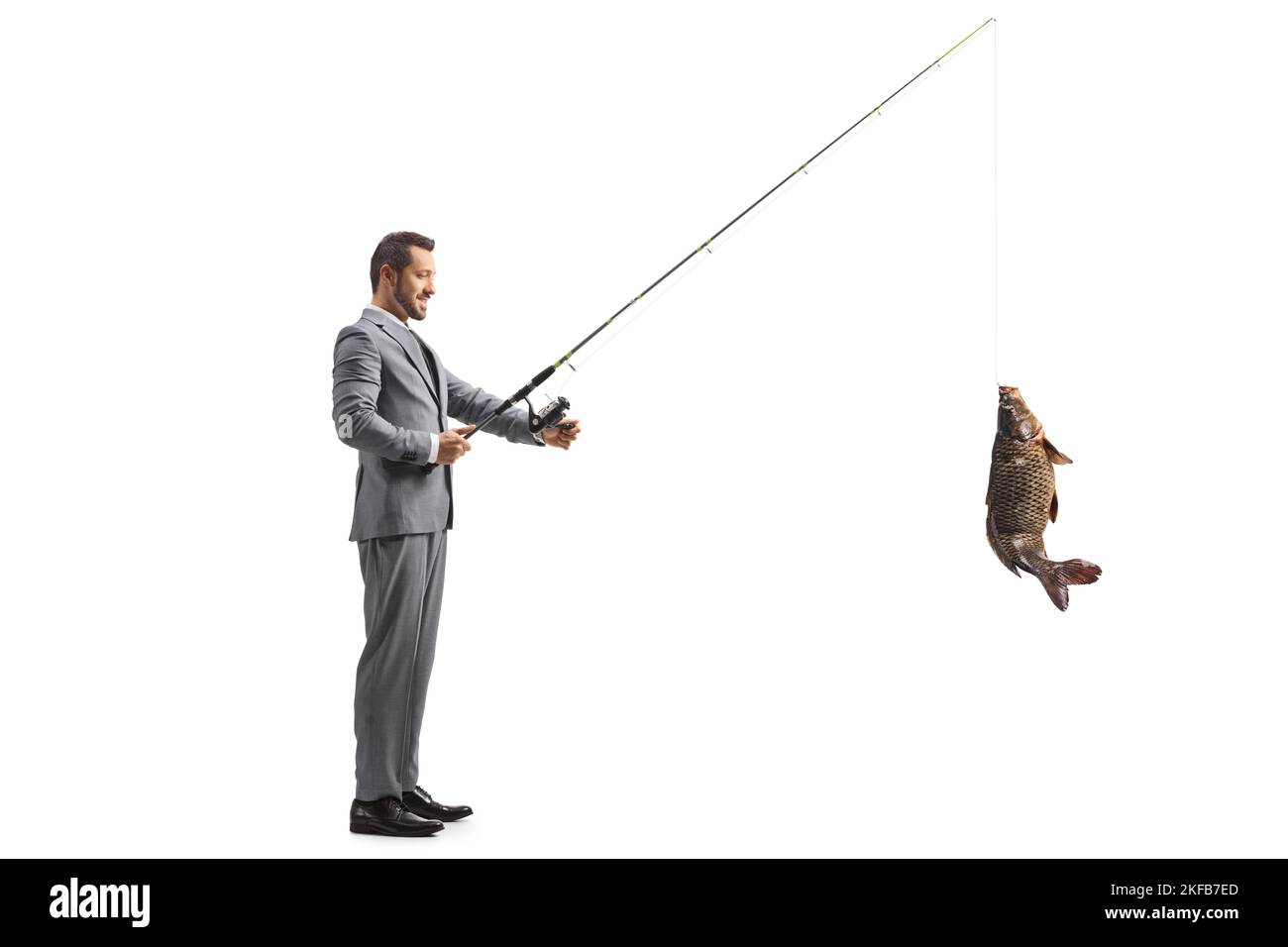 Geschäftsmann fängt einen Karpfenfisch mit einer auf weißem Hintergrund isolierten Angelrute Stockfoto
