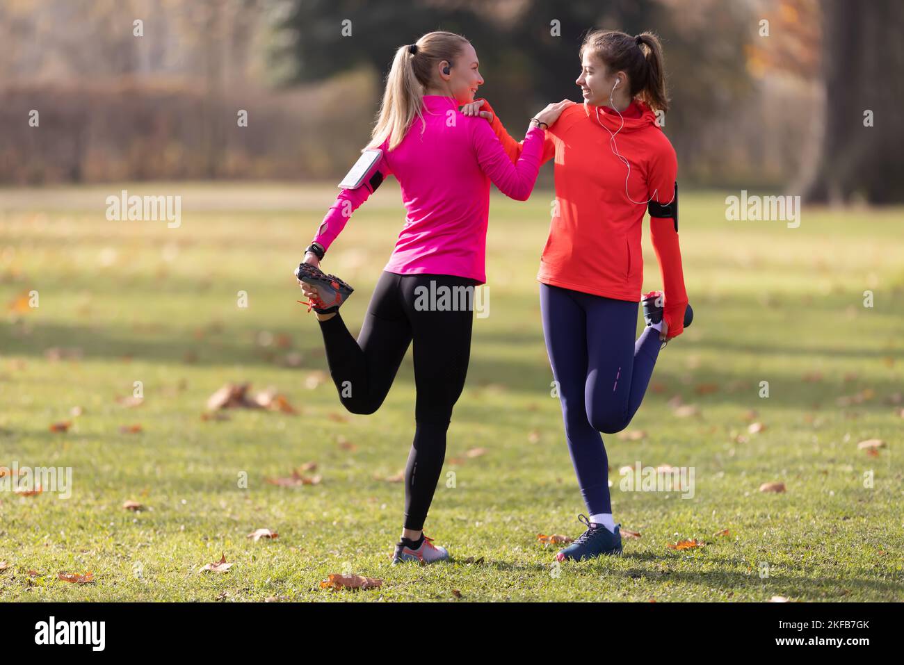 Sportliche Sportlerinnen wärmen sich vor dem Joggen auf und dehnen den Unterkörper im Park. Stockfoto