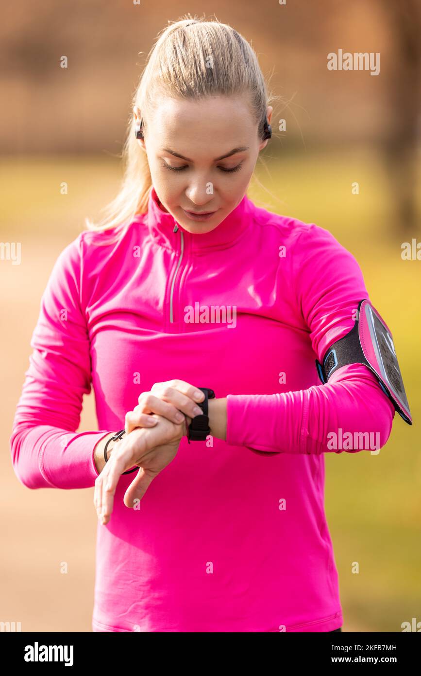 Eine junge Sportlerin schaltet ihre Smartwatch vor dem Laufen ein. Stockfoto