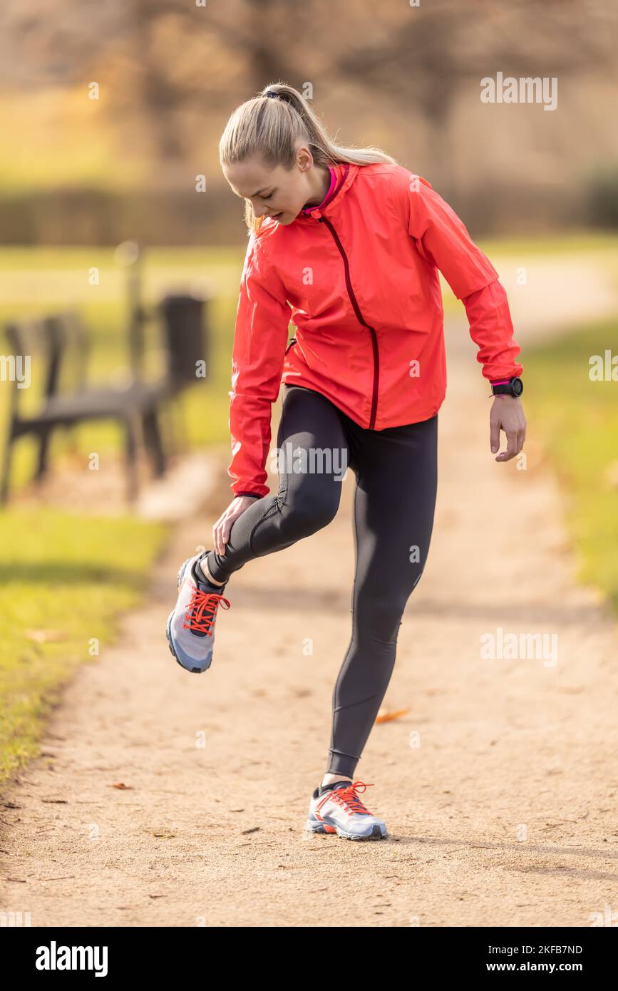 Eine junge Sportlerin verstauchte ihr Kalb beim Laufen, sie hält es vor Schmerzen. Stockfoto