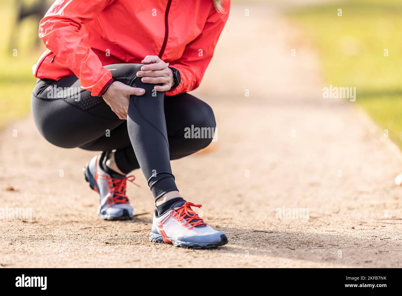 Eine junge Sportlerin verstauchte sich beim Laufen das Knie, sie hält es vor Schmerzen. Stockfoto