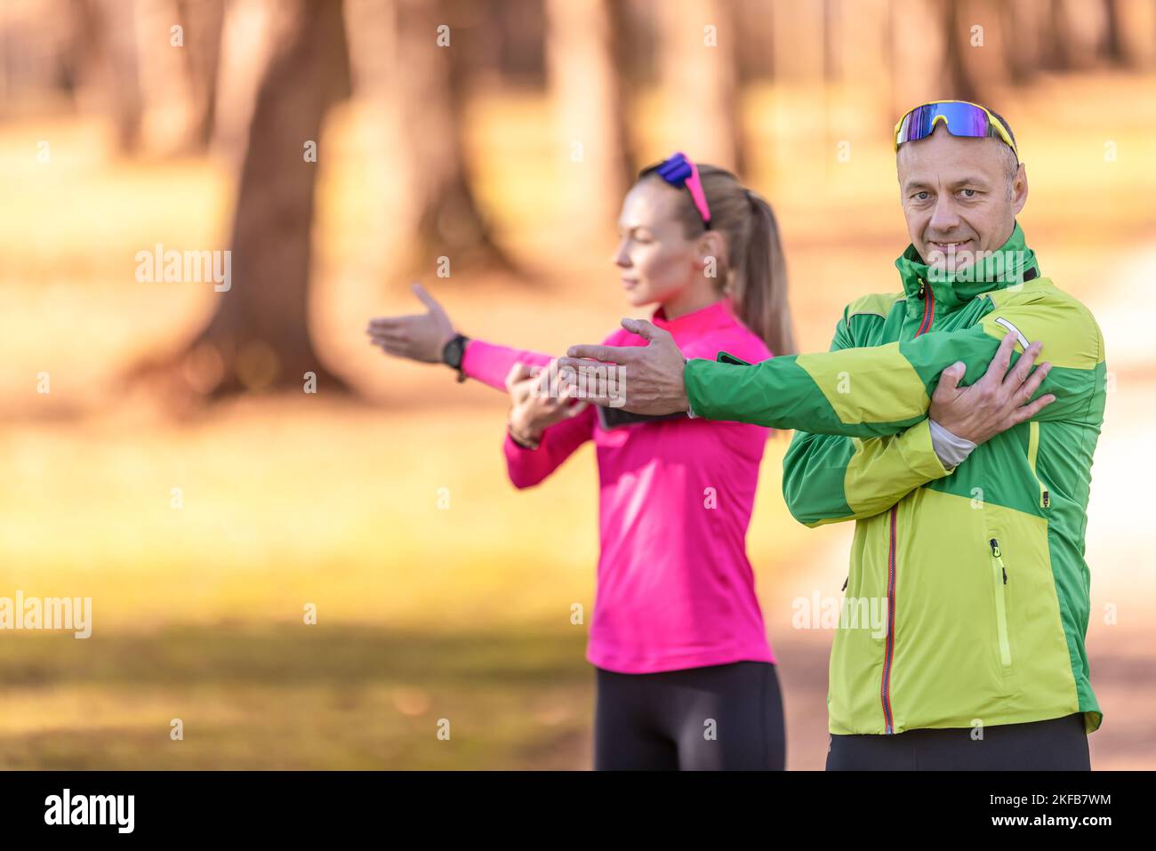 Zwei Amateur-Athleten reifen Mann und junge Frau wärmen sich vor dem Joggen auf und machen Oberkörper-Stretching im Park. Stockfoto