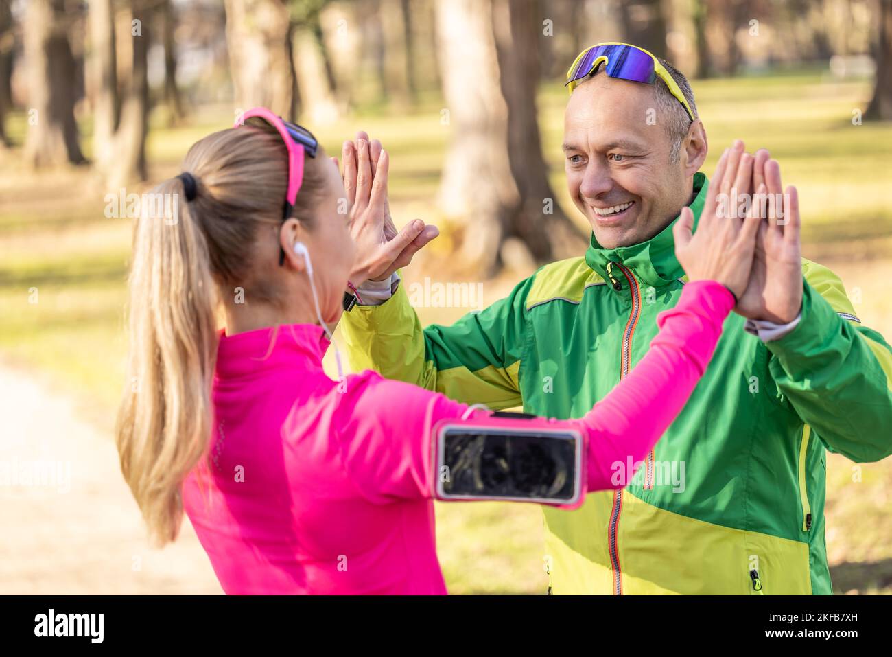 Ein reifer Mann und eine junge Frau unterstützen sich gegenseitig und geben High-Five nach einem Lauf. Stockfoto
