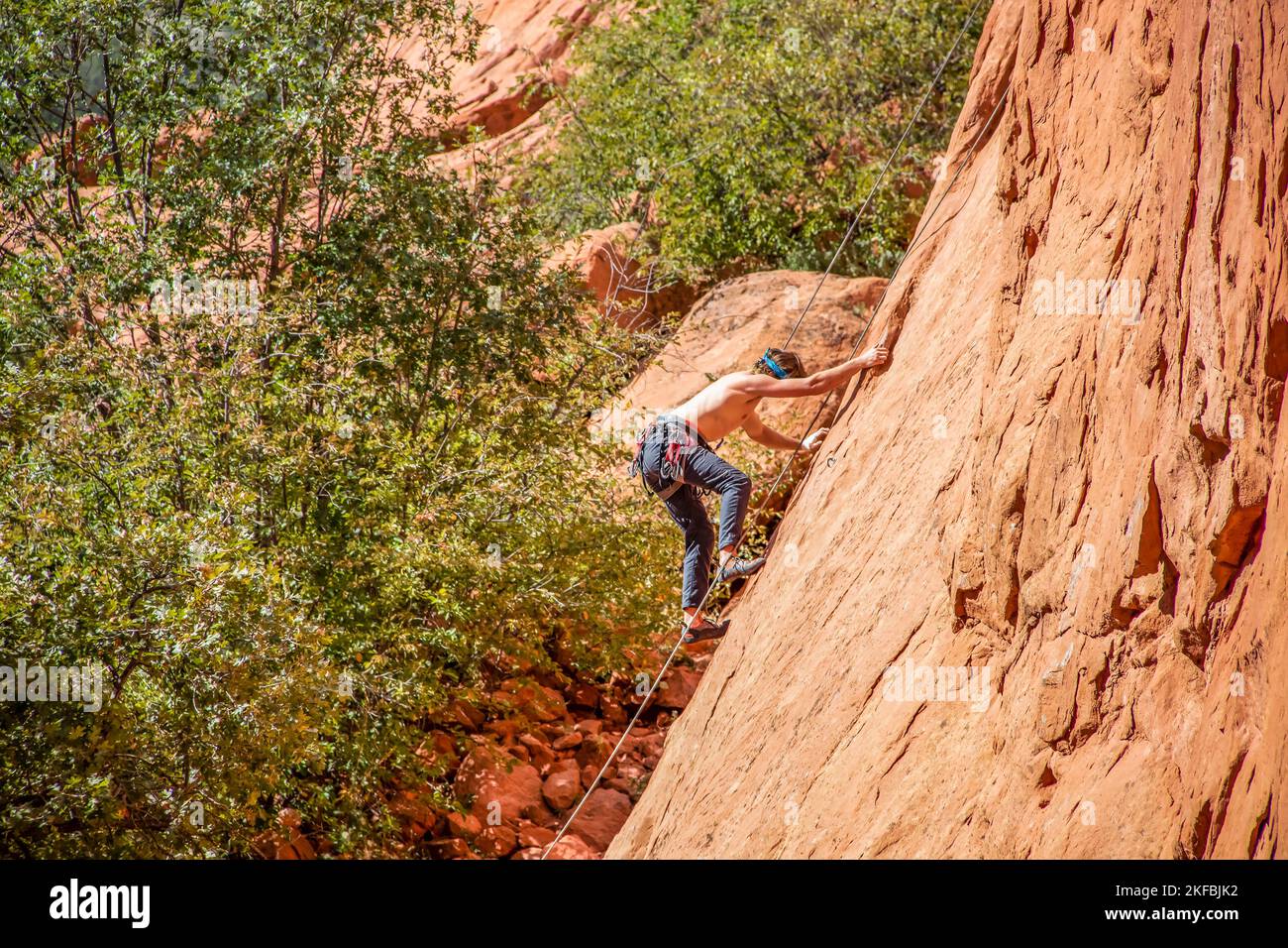 Der Mensch klettert am Garden of the Gods in der Nähe der Rocky Mountains auf eine schiere Sandsteinklippe - kein Hemd mit Seilen und Ausrüstung Stockfoto