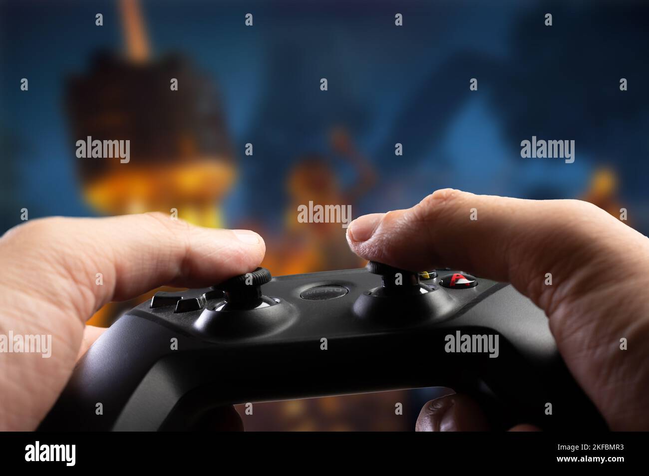 Nahaufnahme. Ein Gamer mit einem GAM22ICB-Joystick spielt ein Videospiel mit Freunden auf einem Großbildfernseher. Spielstrategie, neue drahtlose Technologien, Jugendkultur Stockfoto