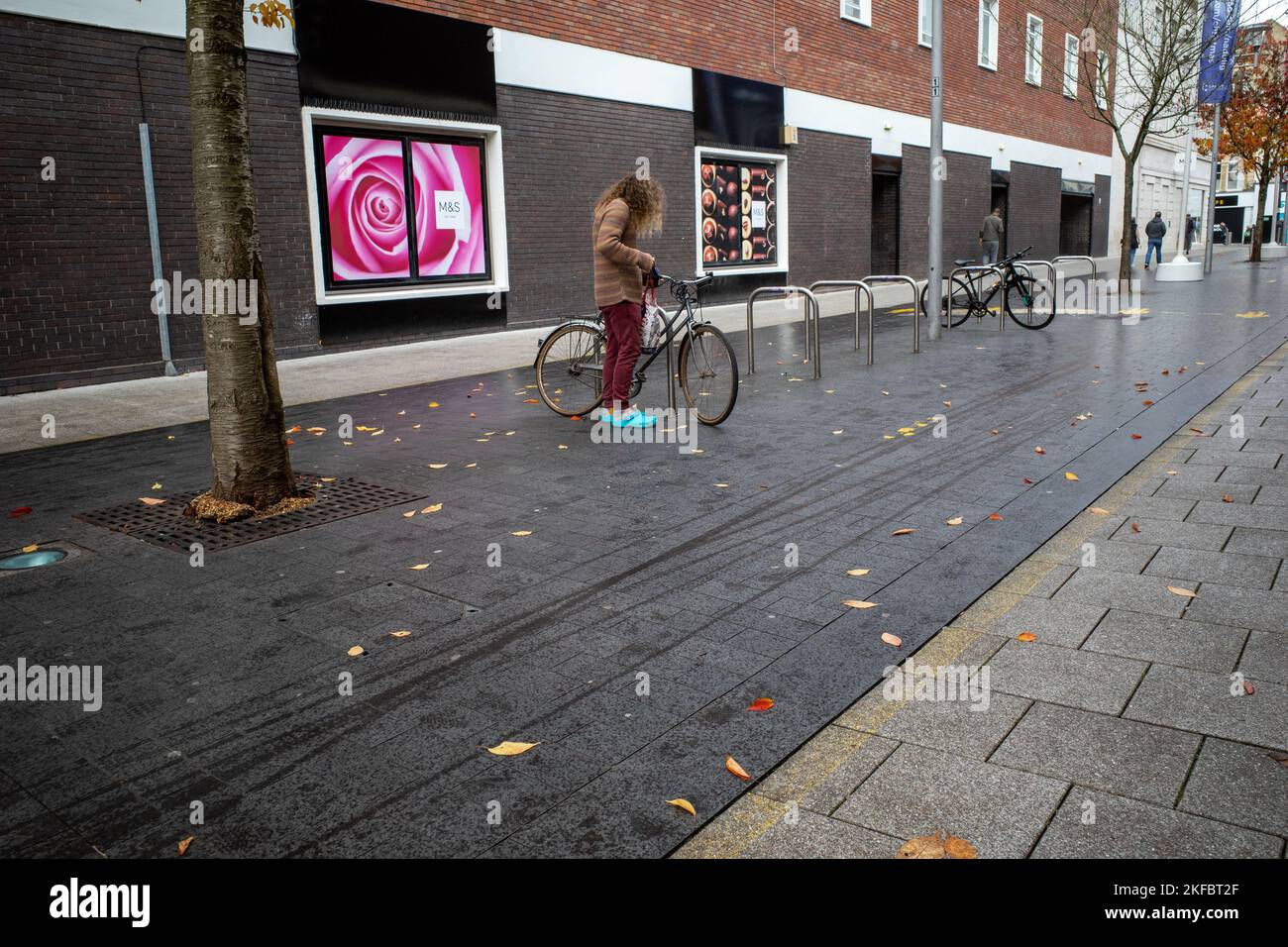 Langhaariger Mann, der sein Fahrrad in Cardiff, Großbritannien, entriegelt Stockfoto