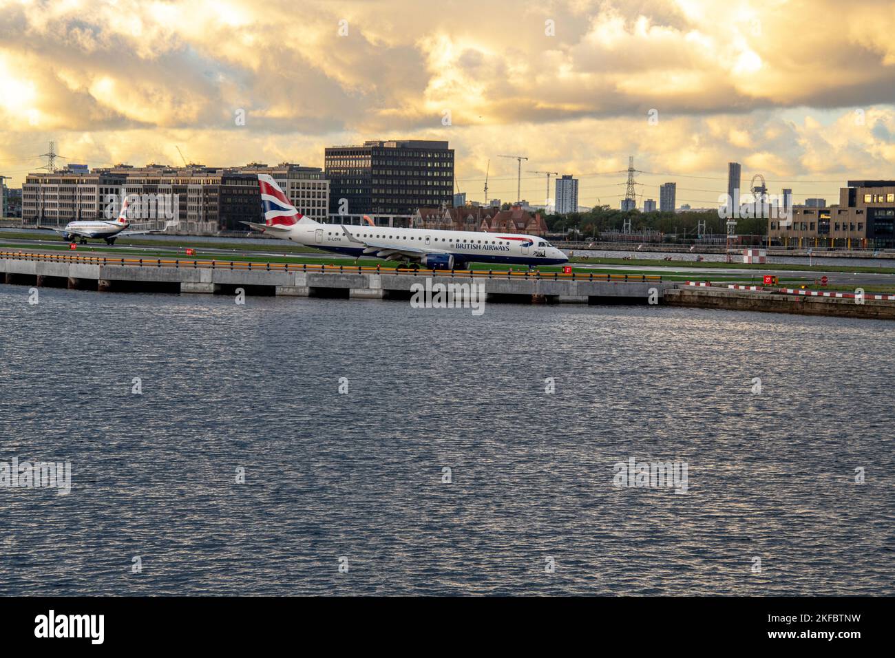 Ein Embraer von British Airways wartet auf den Start, während ein anderer am London City Airport landet. Stockfoto