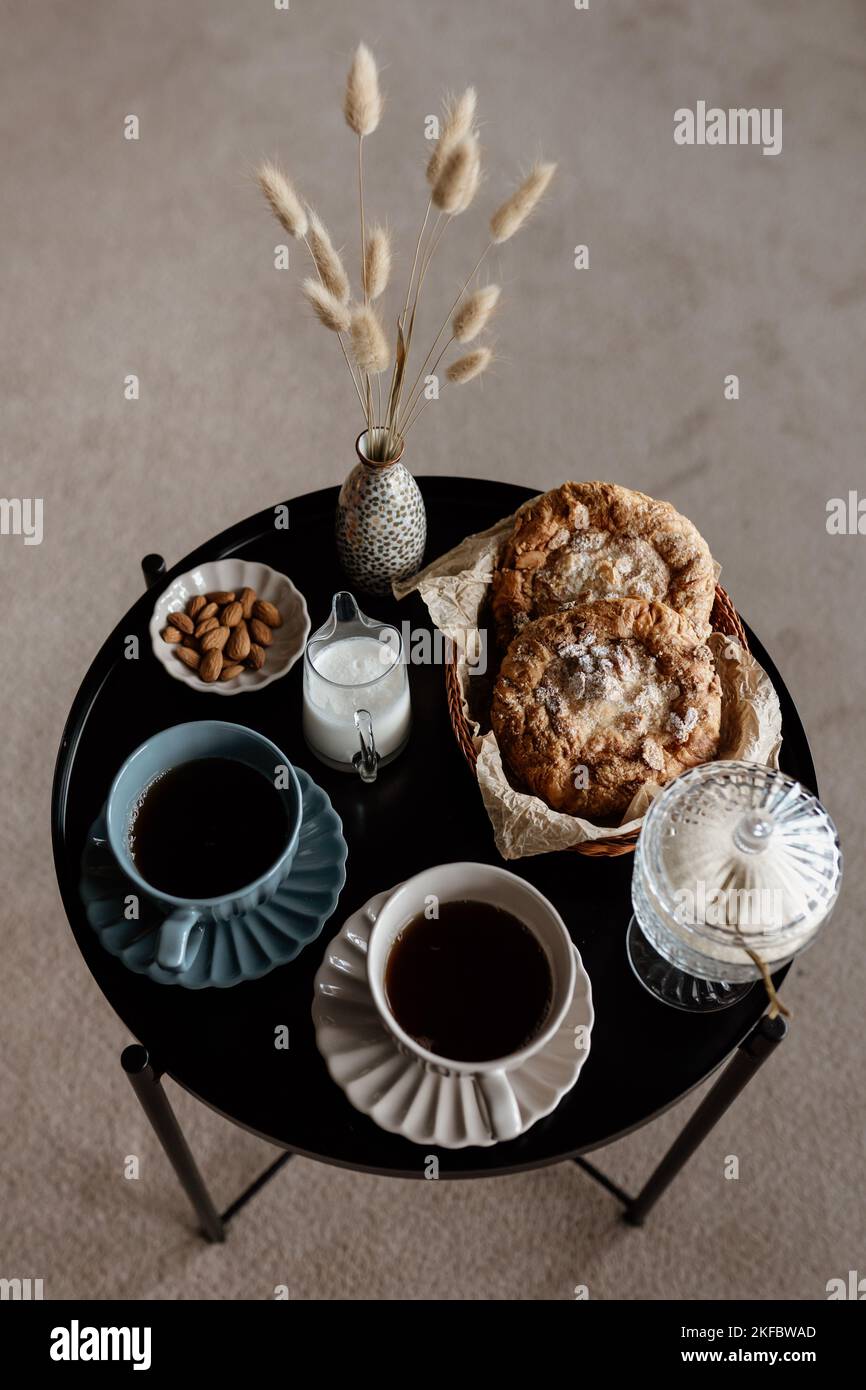 Ästhetisches Frühstück. Milchkaffee, Milchtee, Zucker, Mandel-, Mandelkuchen, Kekse, Marzipane und Puffs. Englisches Frühstück in einem gemütlichen Zuhause. Herbststimmung. Stockfoto
