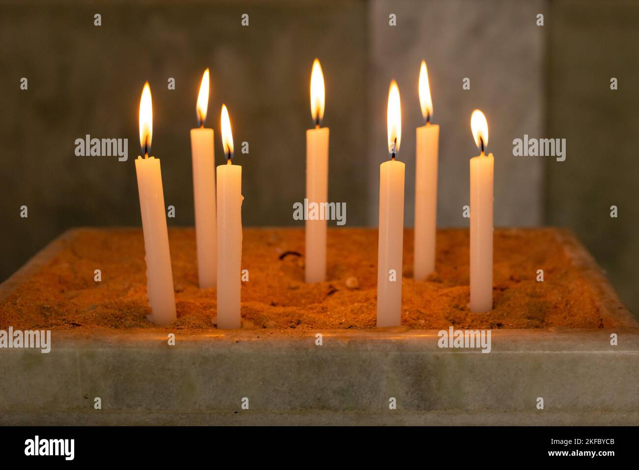 Goiânia, Goias, Brasilien – 12. November 2022: Mehrere brennende Kerzen in einem Sandhalter in der Kirche. Kerzen im Tempel entzündet, heiliges Feuer. Stockfoto