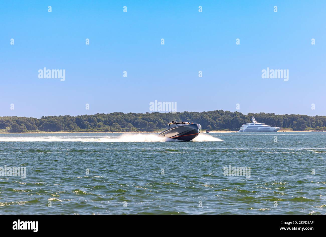Motorboot ist unterwegs mit einer großen Yacht in der Ferne Stockfoto
