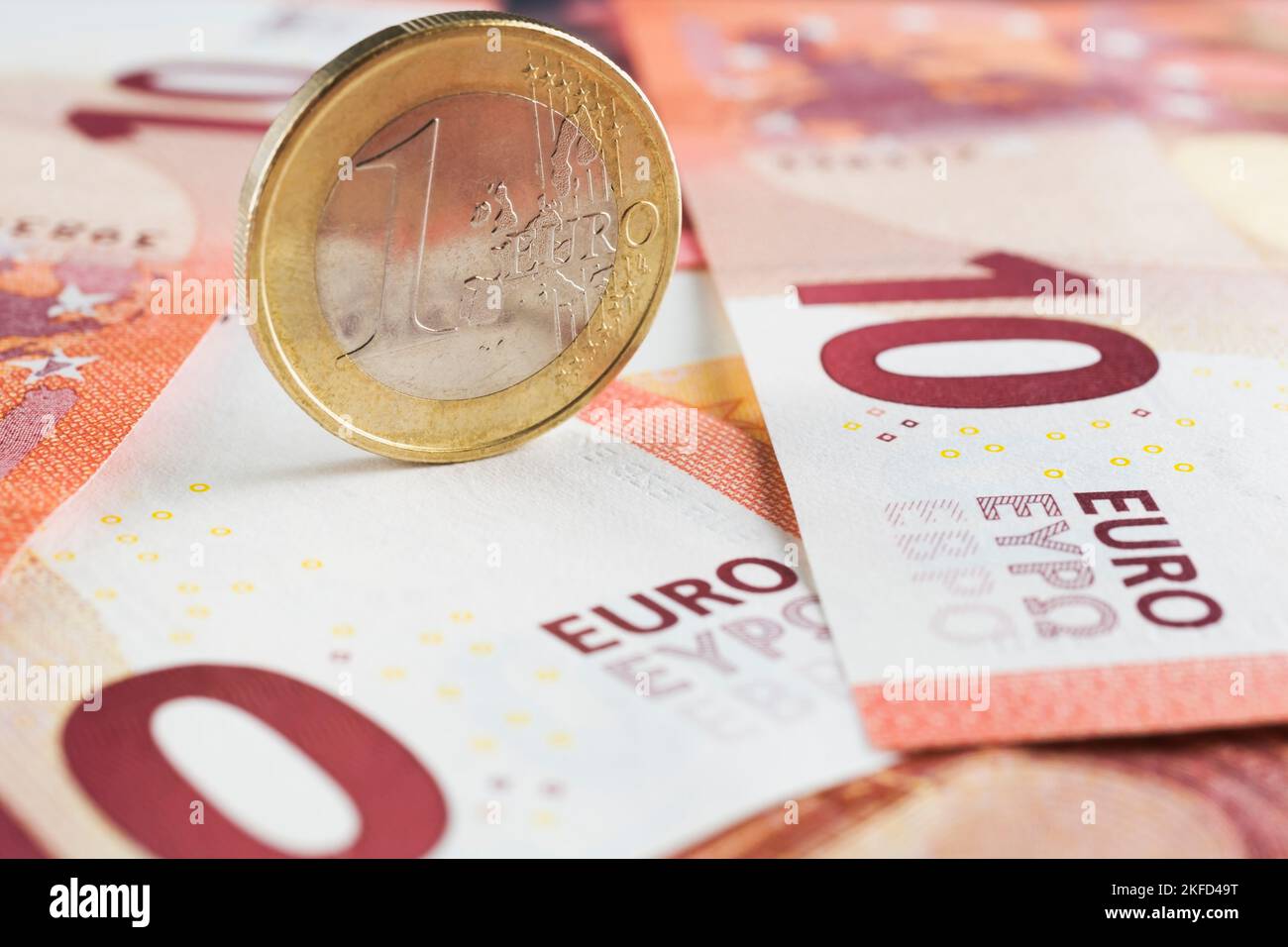 Aufrechte eine-Euro-Münze auf zehn Euro-Banknoten in Papierwährung. Stockfoto
