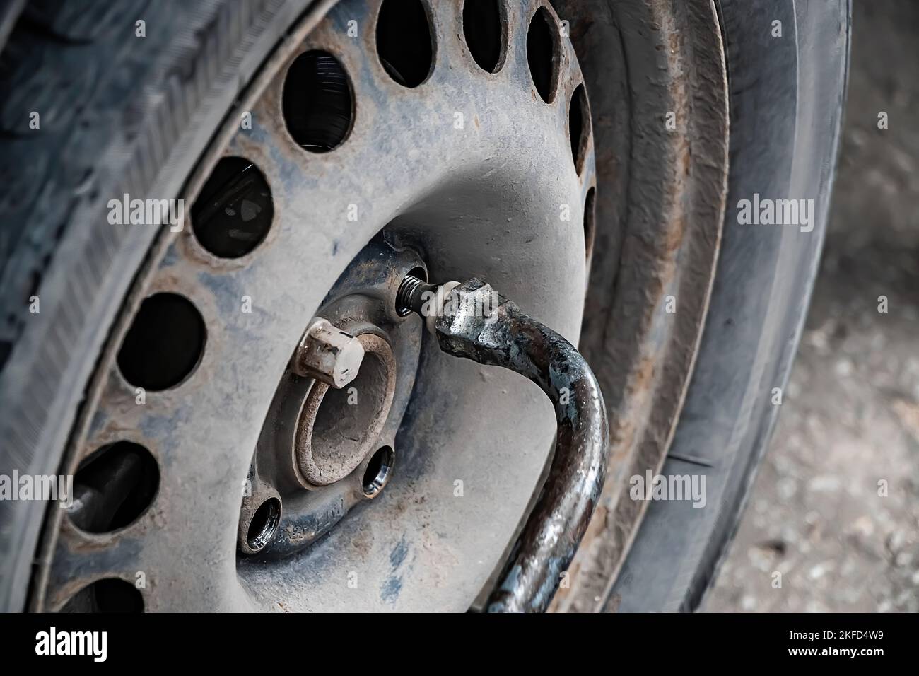 Der Automechaniker wechselt das Rad des alten Autos. Der Mann wechselt nach dem Ausfall den Reifenschaden. Nothilfe am Straßenrand. Nahaufnahme des Autorads. Stockfoto