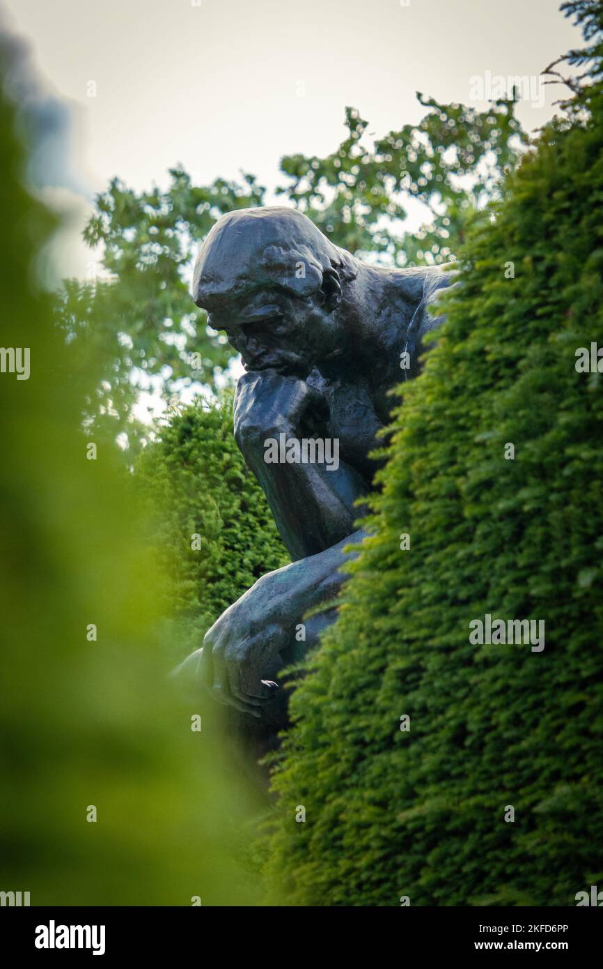 Eine vertikale Aufnahme der von grünen Bäumen umgebenen Denker-Statue in Paris, Frankreich Stockfoto
