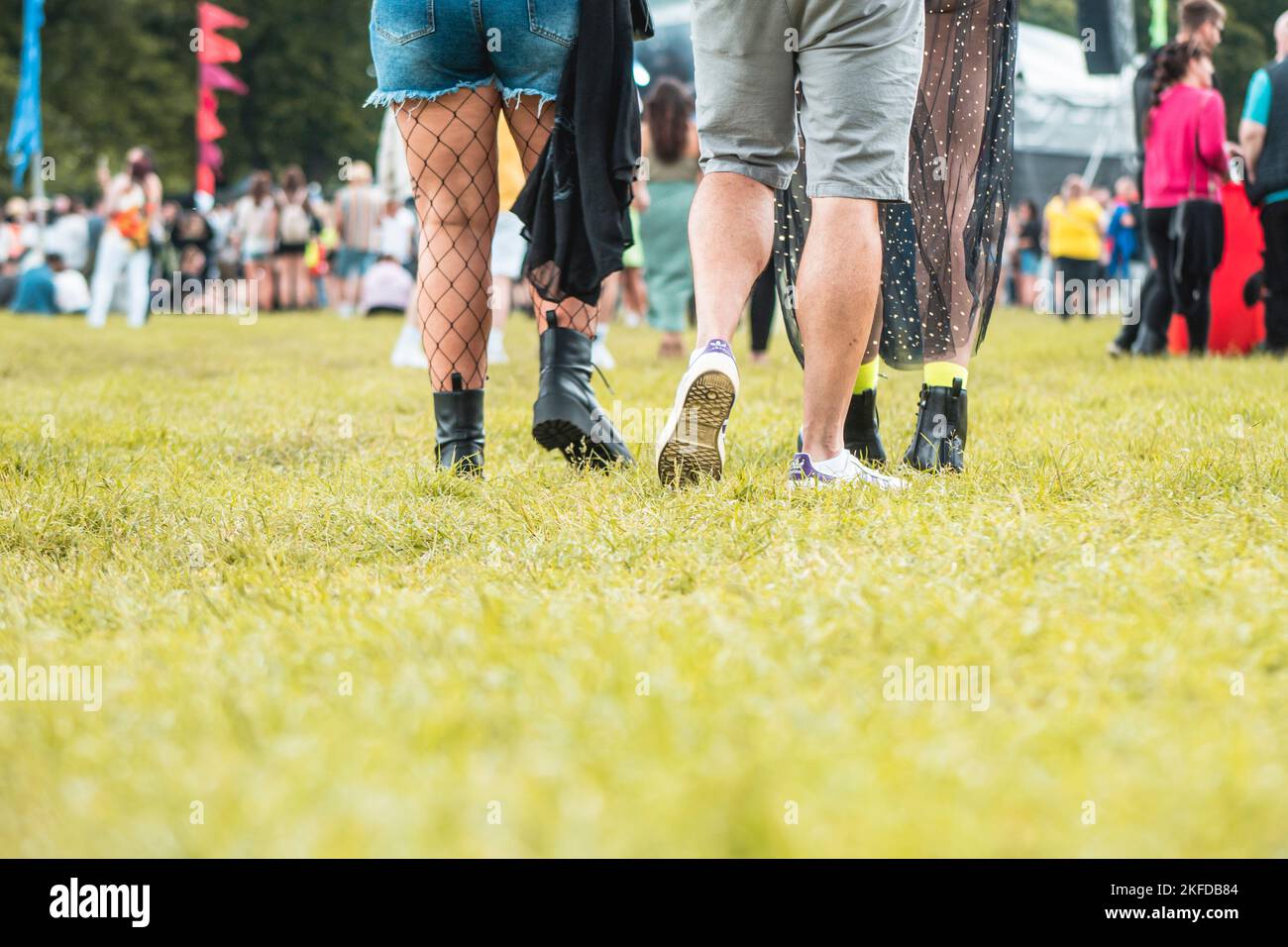 Eine Fokusaufnahme der Beine von drei Personen, die bei einem Festival zur Menge gehen. Stockfoto