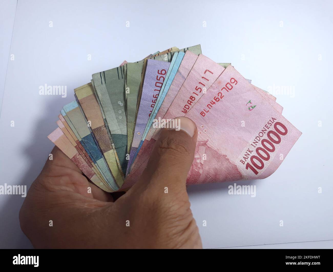 Nahaufnahme isoliert auf weißer Hand, mit mehreren auf Rupien lautenden Banknoten. Rupiah ist die Währung Indonesiens Stockfoto