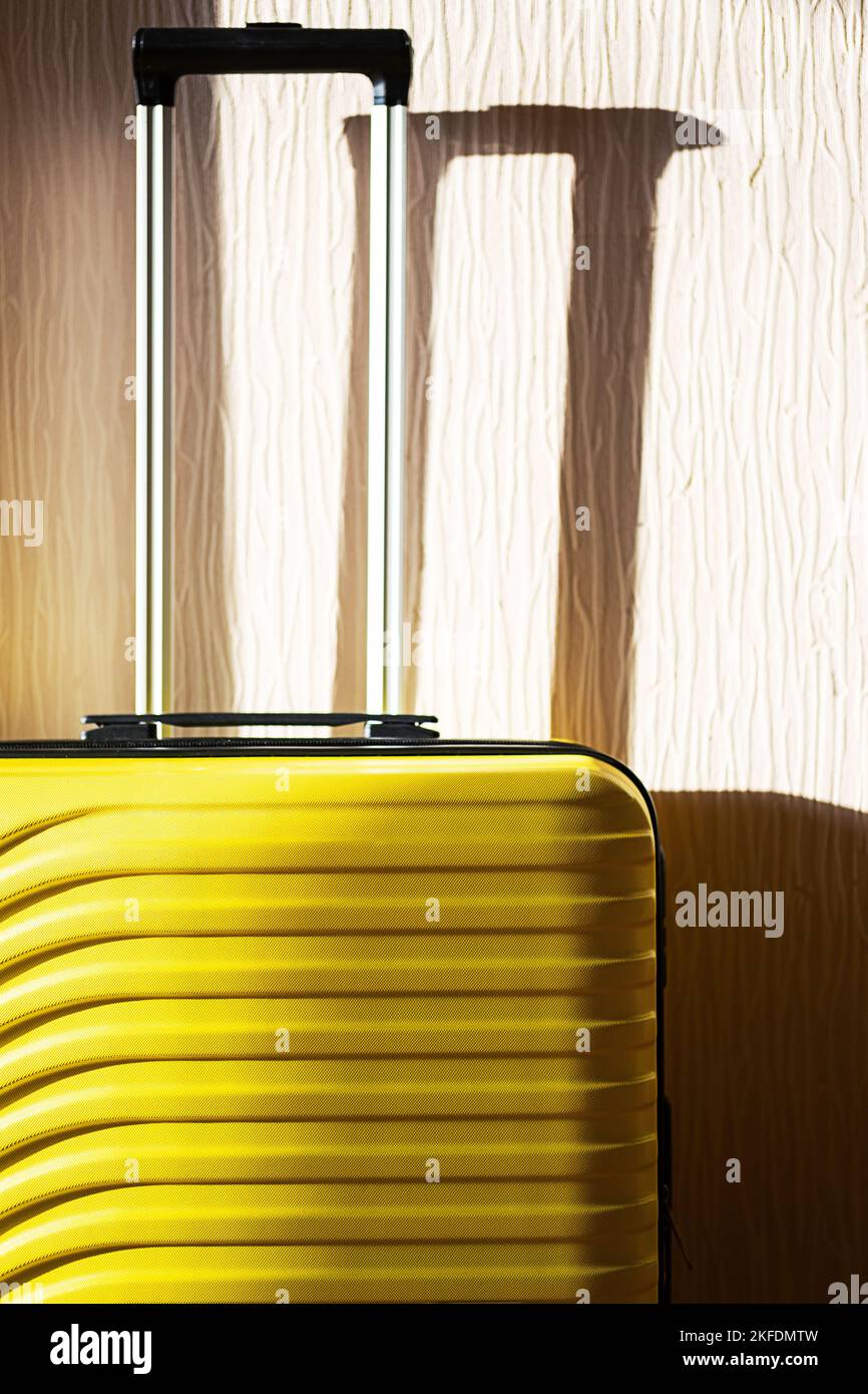 Gelber Koffer an der Wand. Reisetasche, Nahaufnahme. Stockfoto