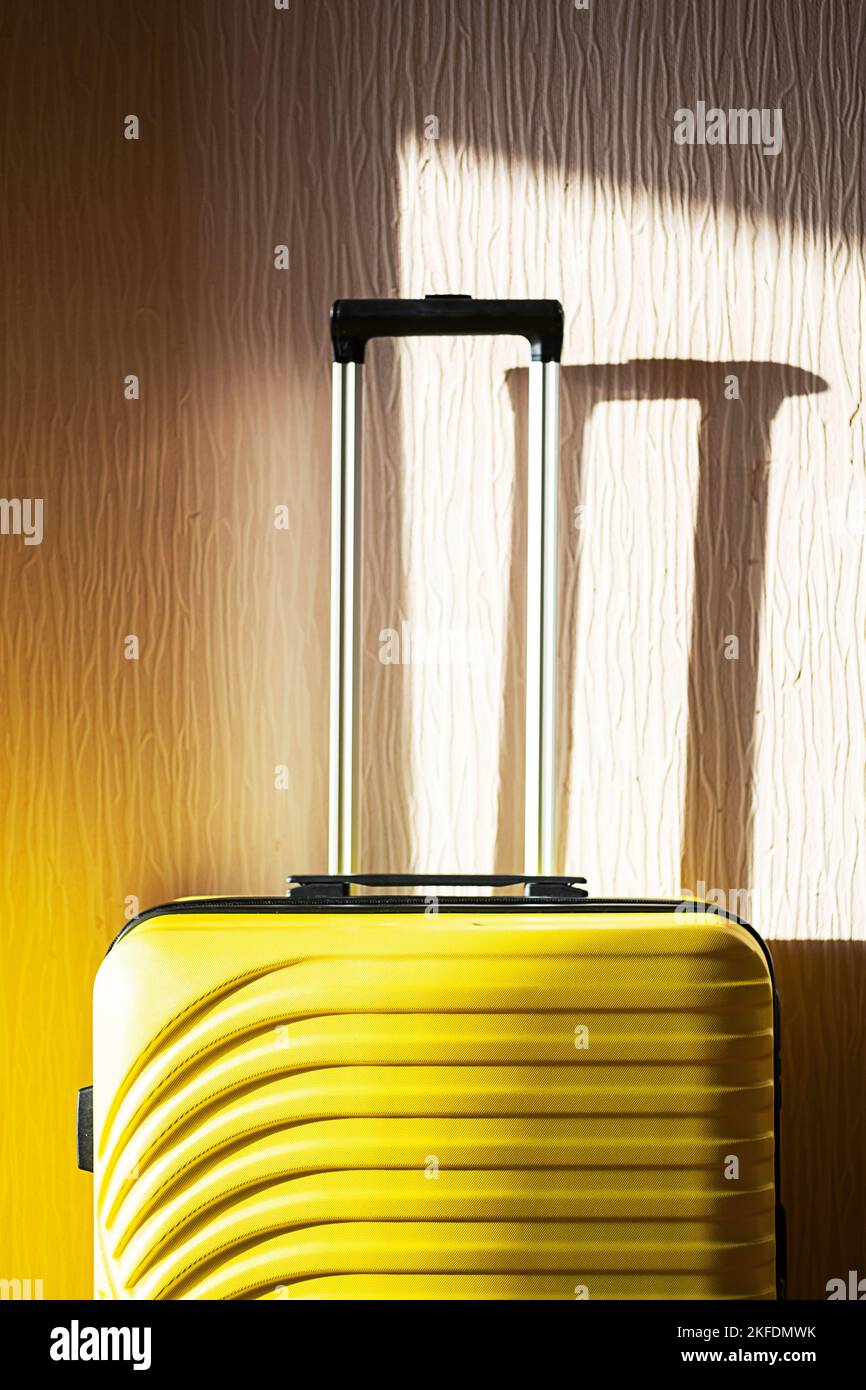 Gelber Koffer an der Wand. Reisetasche, Nahaufnahme. Stockfoto