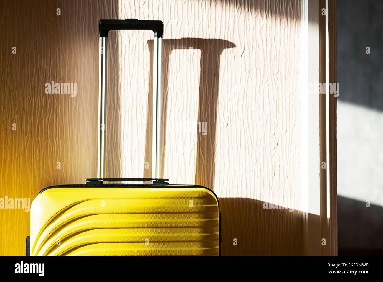 Gelber Koffer an der Wand. Reisetasche, Nahaufnahme. Stockfoto