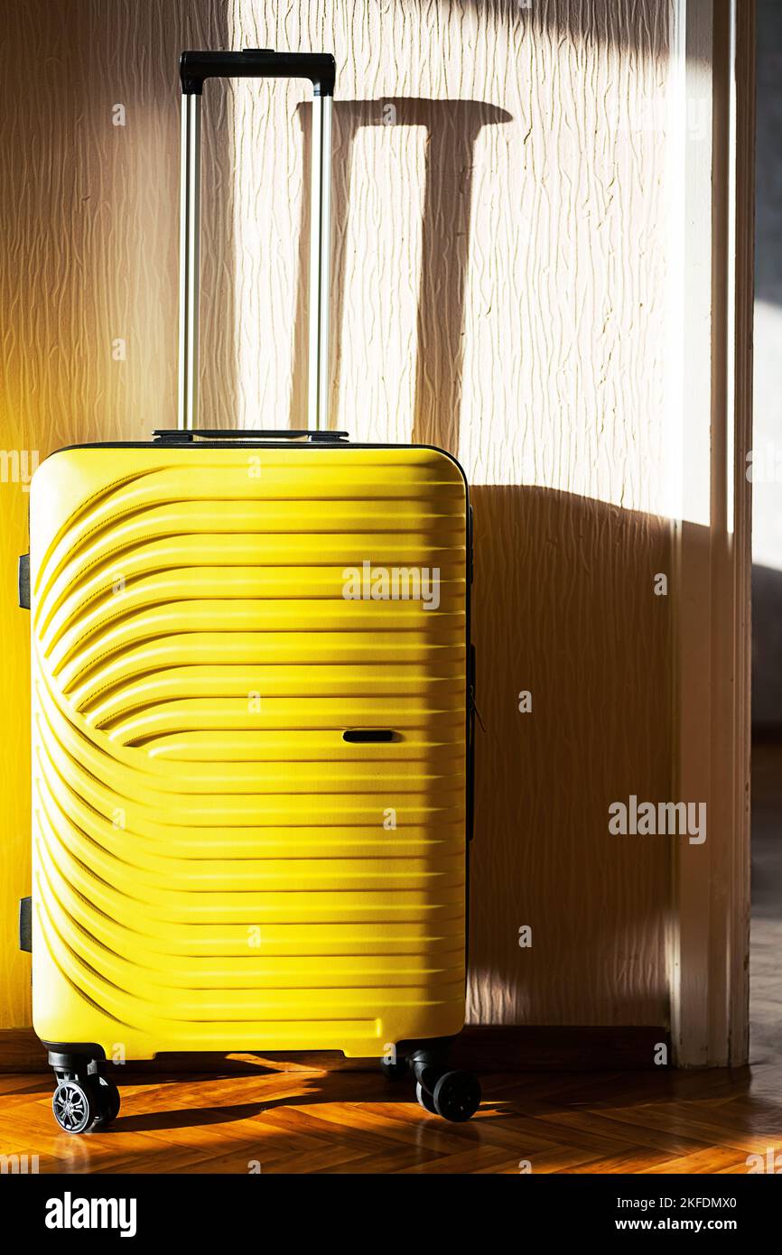 Gelber Koffer an der Wand. Reisetasche, Nahaufnahme. Stockfoto