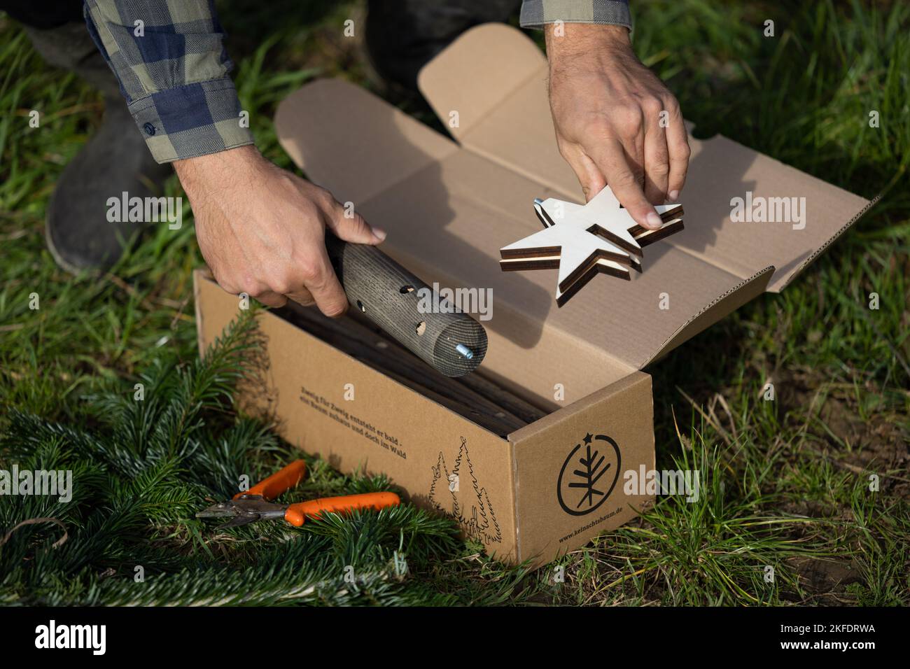 10. November 2022, Niedersachsen, Osnabrück: Erfinder Nico Stisser packt einen seiner alternativen Weihnachtsbäume aus einer Kiste. Der Keinachtsbaum, der die klassische Tanne ersetzt, besteht aus einem Holzstab, der jedes Jahr zu Weihnachten mit neuem Tannengrün bestückt wird. Die Idee des Osnabrücker Start-up stieß auf großes Interesse.(to dpa: 'Der Keinachtsbaum soll die Weihnachtstanne im Wald lassen') Foto: Friso Gentsch/dpa Stockfoto