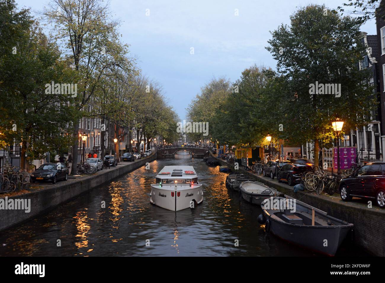 Ein Touristenboot auf einem Amsterdamer Kanal in der Dämmerung, Amsterdam, Niederlande Stockfoto
