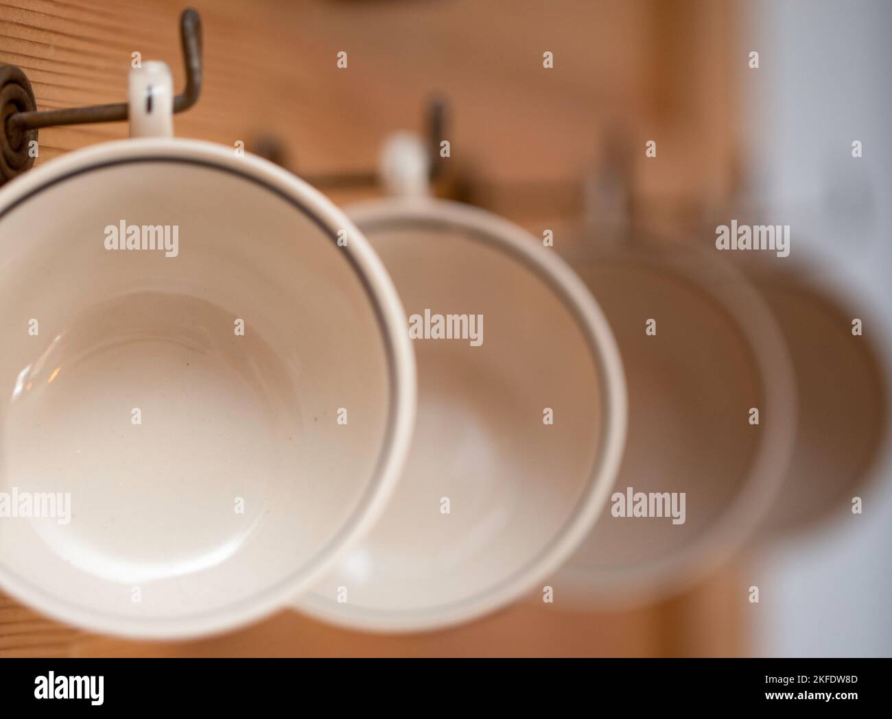 Becher hängen in einer Reihe auf einem Holzregal Stockfoto