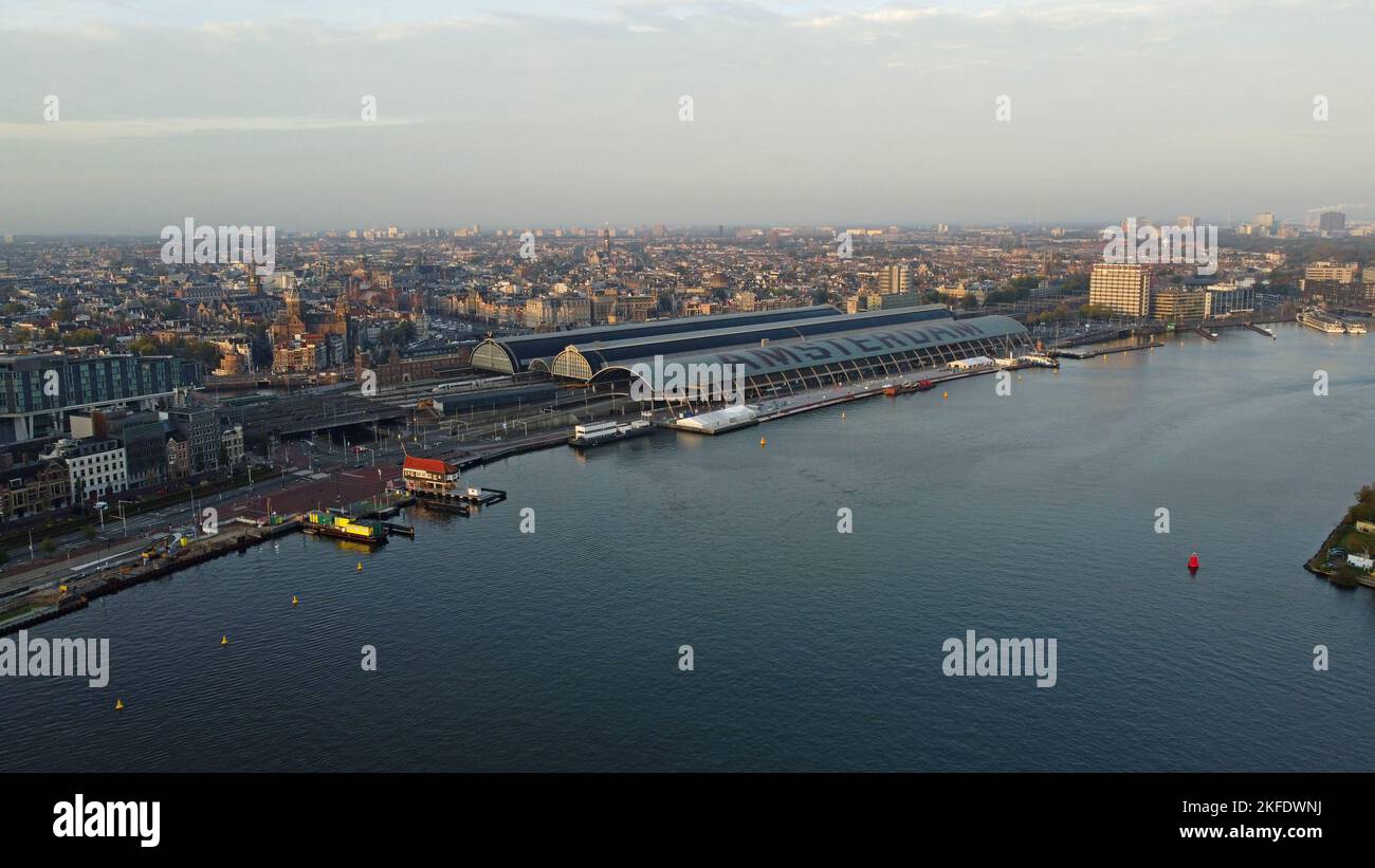 Ein Drohnenfoto aus der Vogelperspektive der IJ docklands und der Amsterdam Centraal Station am Ufer, Amsterdam, Niederlande Stockfoto