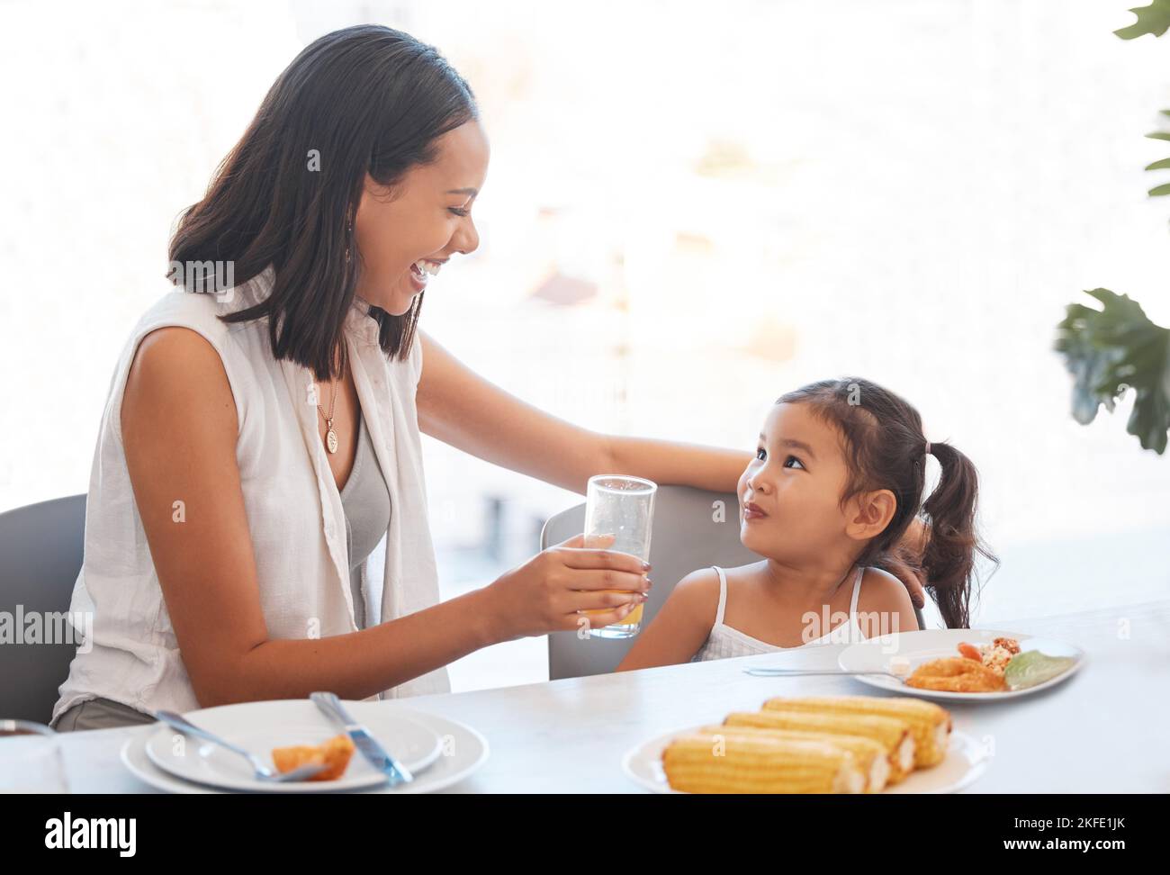 Frau, Essen und Essen zu Hause für Gesundheit, Wellness und Ernährung Ernährung am Esstisch. Essen, Mittagessen und Mutter und Tochter essen und trinken Saft Stockfoto
