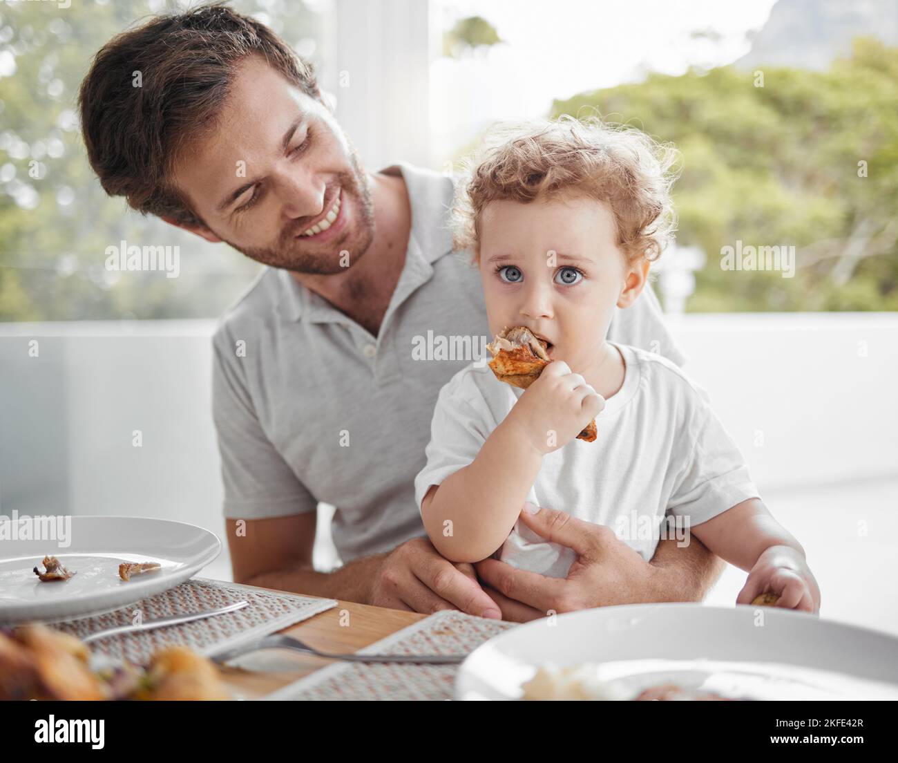 Vater, Baby und Essen am Mittagstisch für die Bindung zusammen in Familie zu Hause mit hungrigen Kind. Essen, Gesundheit und Wellness von unabhängigen und niedlichen Kind Stockfoto