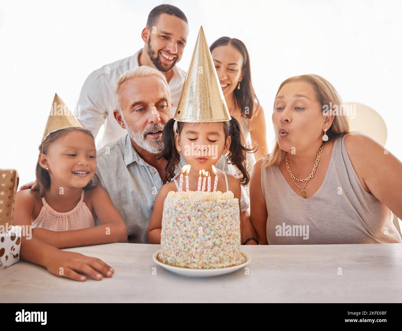 Kindergeburtstag, Geburtstagskuchen oder Kerzen zum Ausblasen mit Mutter, Vater und älteren Großeltern zu Hause. Spaß, aufgeregt oder glücklich Kinder und Stockfoto