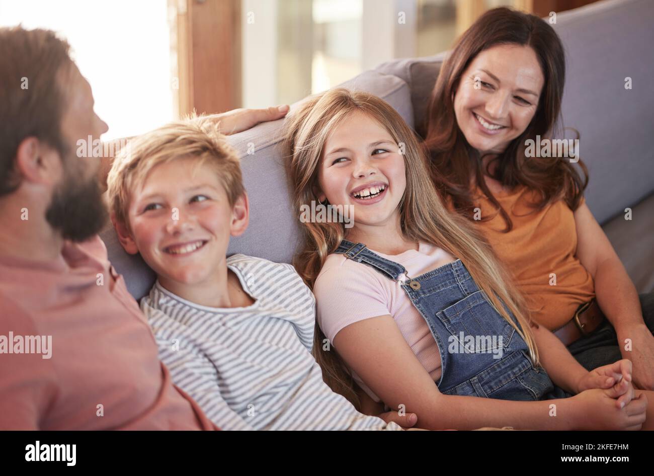 Glücklich, Liebe und Eltern auf einem Sofa mit ihren Kindern reden, lachen und sich im Wohnzimmer verbinden. Glück, Lächeln und Familie in Comic oder lustig Stockfoto