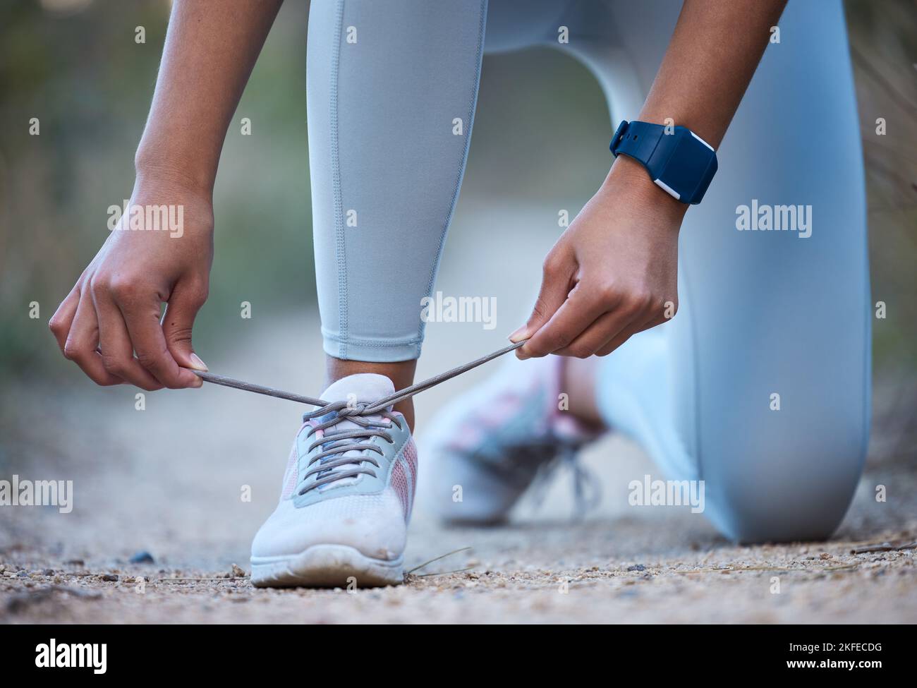 Fitness, Bewegung und Frau Krawatte Schuh nach dem Laufen, Training und Marathon-Training in der Natur. Sport, Wellness und Nahaufnahme der Hände binden Spitze auf Stockfoto