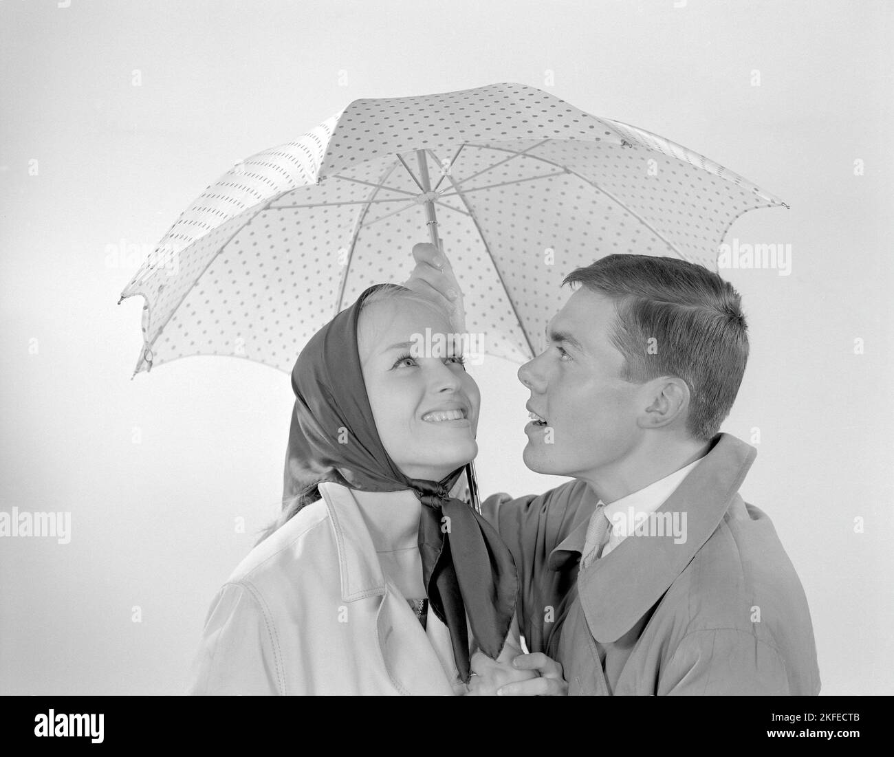 1960s Paar. Ein glückliches lächelndes Paar steht unter einem Regenschirm. Schweden 1960 Conard Ref. 4254 Stockfoto