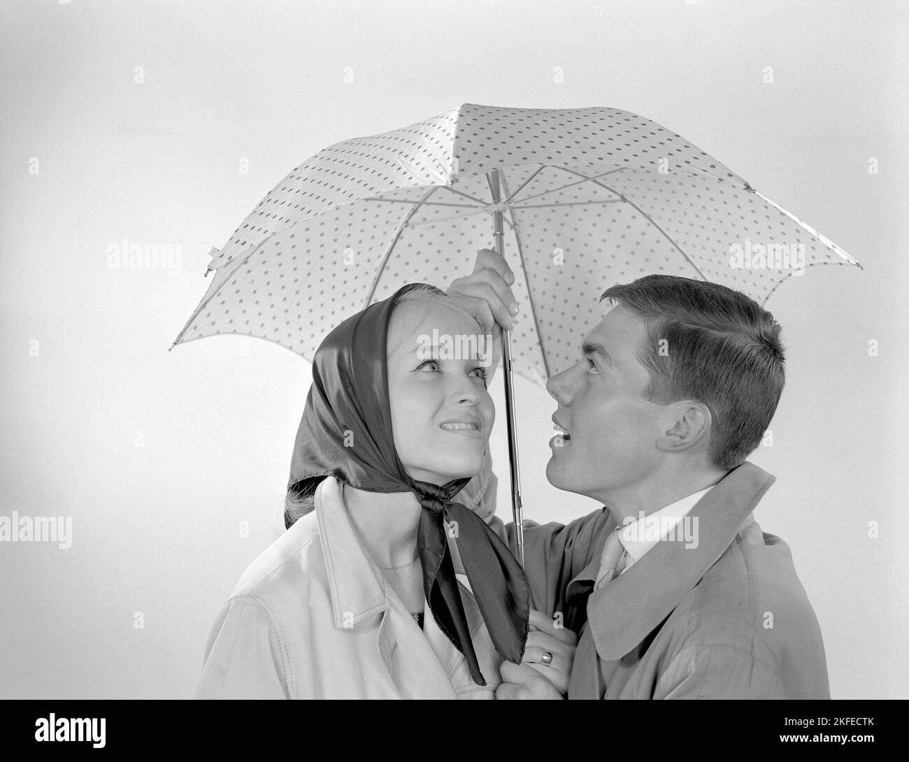 1960s Paar. Ein glückliches lächelndes Paar steht unter einem Regenschirm. Schweden 1960 Conard Ref. 4254 Stockfoto