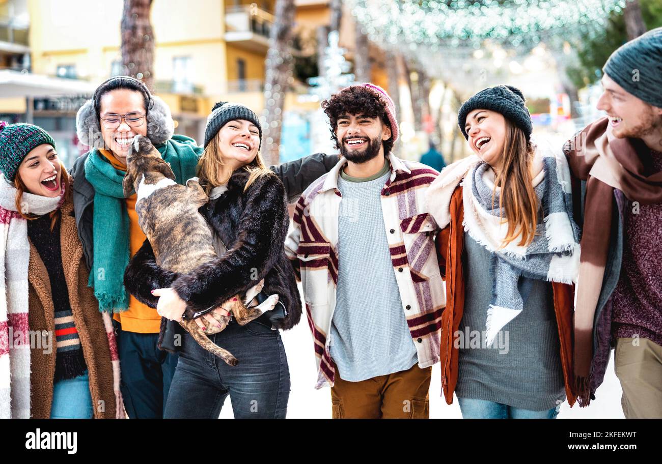 Happy People Group Spaß haben zusammen mit niedlichen Hund im Winterurlaub - Life Style Konzept mit trendigen jungen Freunden tragen Mode-Kleidung Stockfoto
