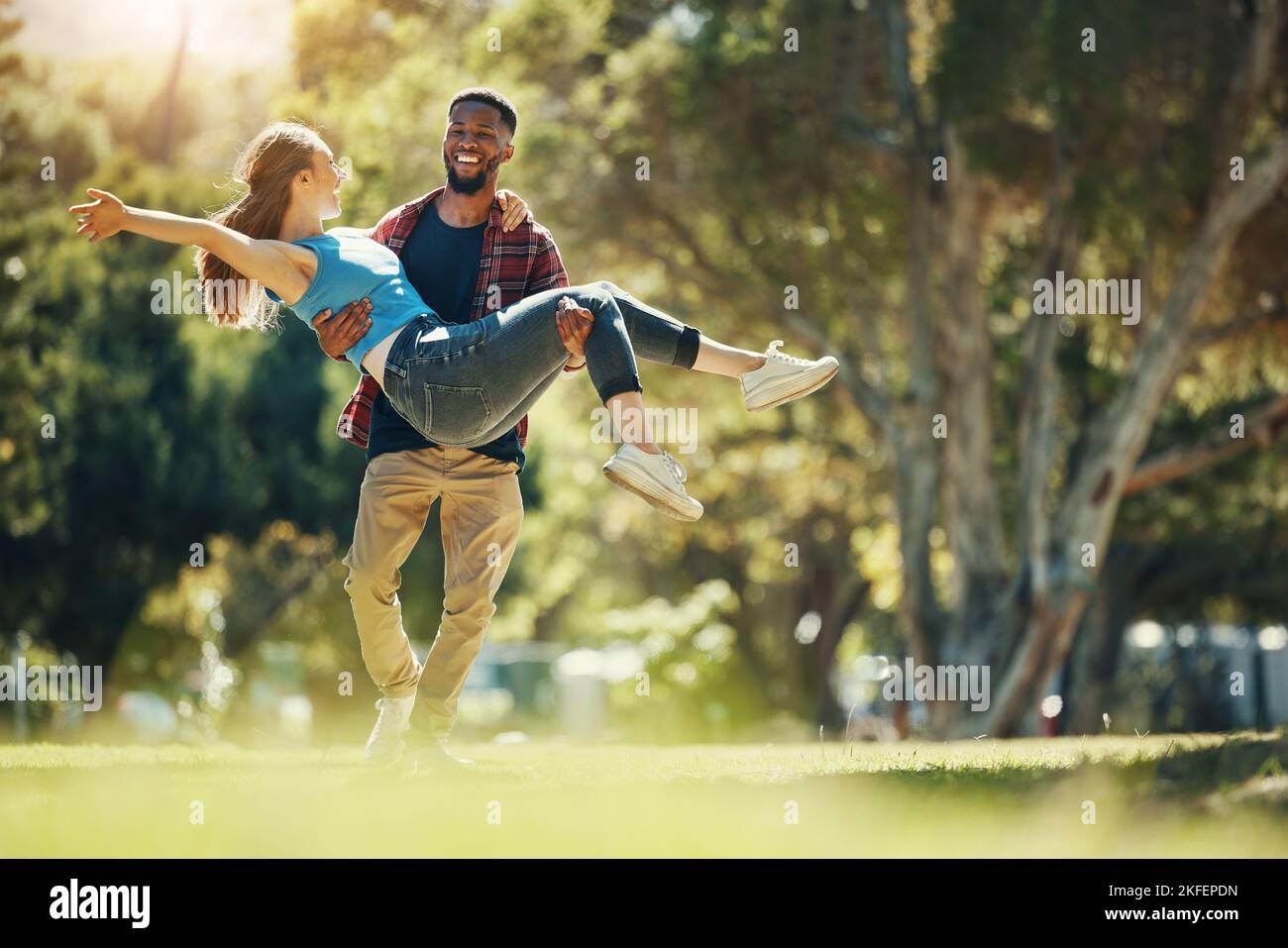 Verrücktes Paar, tragen und glückliches Lächeln, Spaß und genießen Sie Datum im Naturpark, Romantik und Sorgfalt beim Laufen zusammen. Interracial Mann, Frau und Liebe mit Stockfoto